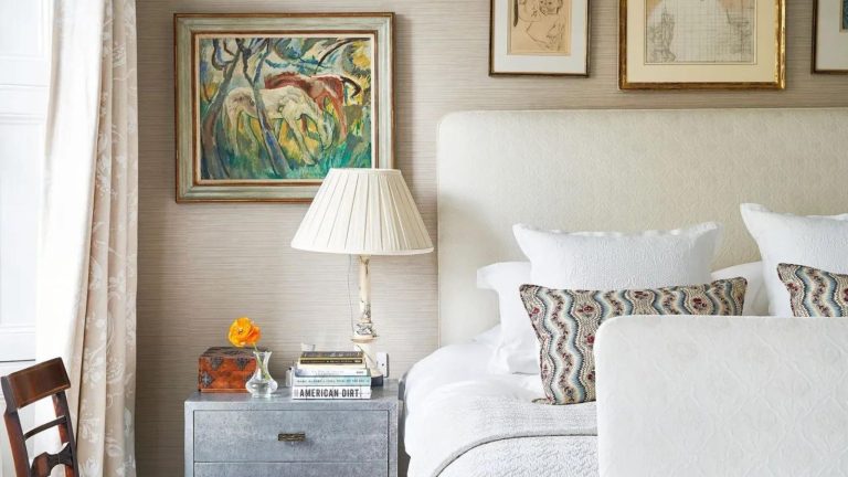 A bed with a beige fabric headboard and metallic bedside drawers
