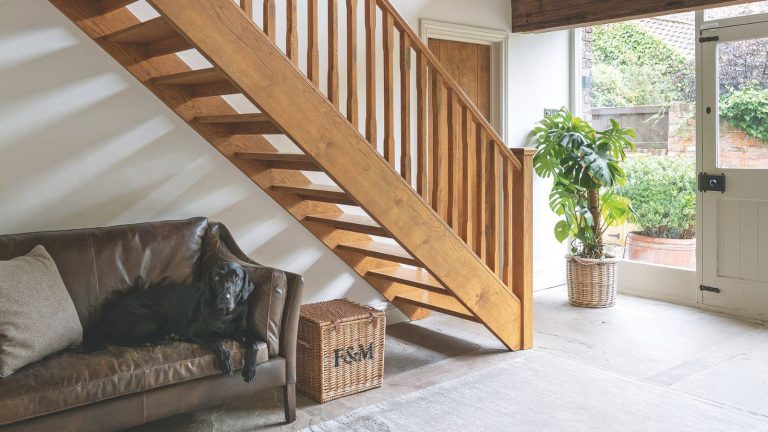 Ce porte-chaussures Joseph Joseph réglable et élégant à 39 $ résout les empilements de chaussures d’hiver dans les entrées compactes The double height stairwell in a barn conversion, a wooden staircase and banister, tiled flooring and glass windows and front door.
