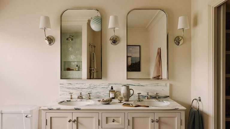 Le seul élément de rangement verrouillable Les organisateurs professionnels disent que les propriétaires l’oublient souvent lorsqu’ils planifient une nouvelle salle de bain – mais ils ne devraient pas le faire A double sink bathroom vanity with two mirrors, and three wall sconces.
