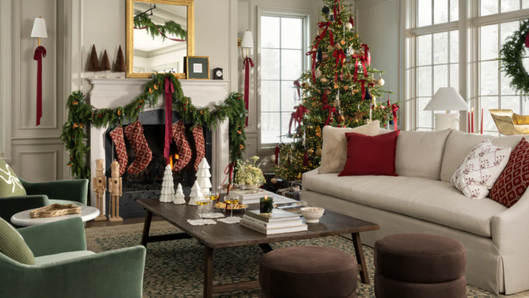 La collection des Fêtes 2025 de Shea McGee contient toutes les pièces dont vous avez besoin pour recréer un Noël nostalgique intemporel – et en ce moment, tout est à 50 % de réduction a living room decorated for Christmas with a tree, garland over the mantel, and lots of decorative objects around the room