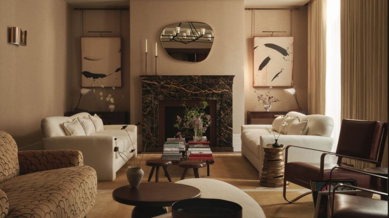 La créatrice Brigitta Spinocchia Freund explique comment elle mélange sans effort l’ancien et le nouveau – elle dit qu’il ne s’agit pas de suivre les tendances mais de créer une histoire Elegant neutral living room with a mix of armchairs and coffee tables and a large dark stone fireplace