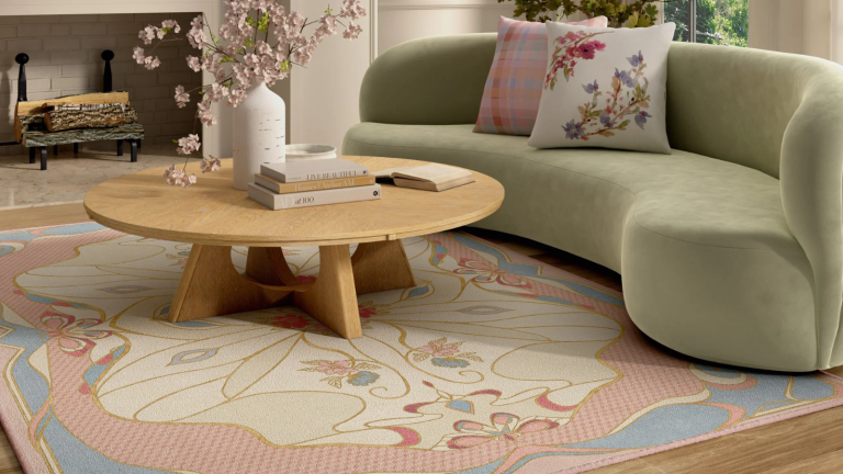 La nouvelle collection « Wicked » de Ruggable capture la nature fantastique du pays d’Oz sous vos pieds et peut rendre chaque pièce de votre maison un peu plus magique a living room with a green couch, an abstract pink rug, a wood coffee table