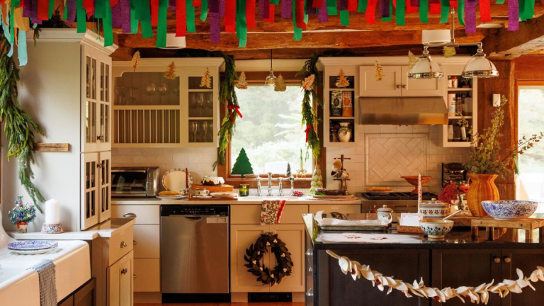 Personne ne décore pour les fêtes comme la famille March – Voici pourquoi la charmante esthétique de Noël des « petites femmes » continue d’inspirer les intérieurs d’aujourd’hui a kitchen decorated for Christmas with various handmade trimmings hanging from the ceiling, the cabinets, and Christmas decor all over the kitchen