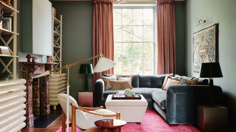 Les 3 tendances de couleurs dépassées que les designers laissent de côté dans leurs schémas en 2026 – et les alternatives plus tendance qu’ils utilisent à la place A living room with teal walls, a bright pink rug, and a teal velvet corner sofa in front of a large window.
