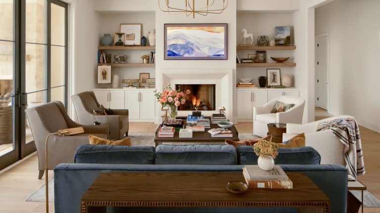 Les concepteurs de styles de sièges inattendus appellent leur « arme secrète » pour un salon plus social cette saison d’accueil neutral living room with a fireplace, built in cupboard and shelves in the alcoves, a blue velvet couch with two bouclé swivel chairs