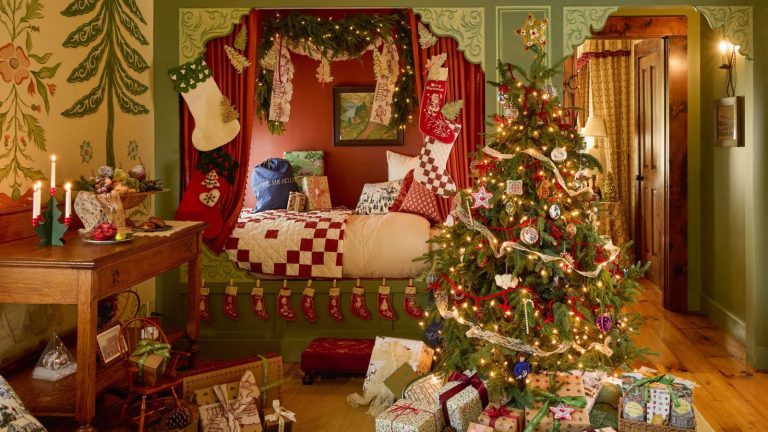 a bed nook bedroom at the six bells inn styled with red and green folk aesthetic and dressed for christmas with stockings, patchwork accessories, a christmas tree and wrapped presents
