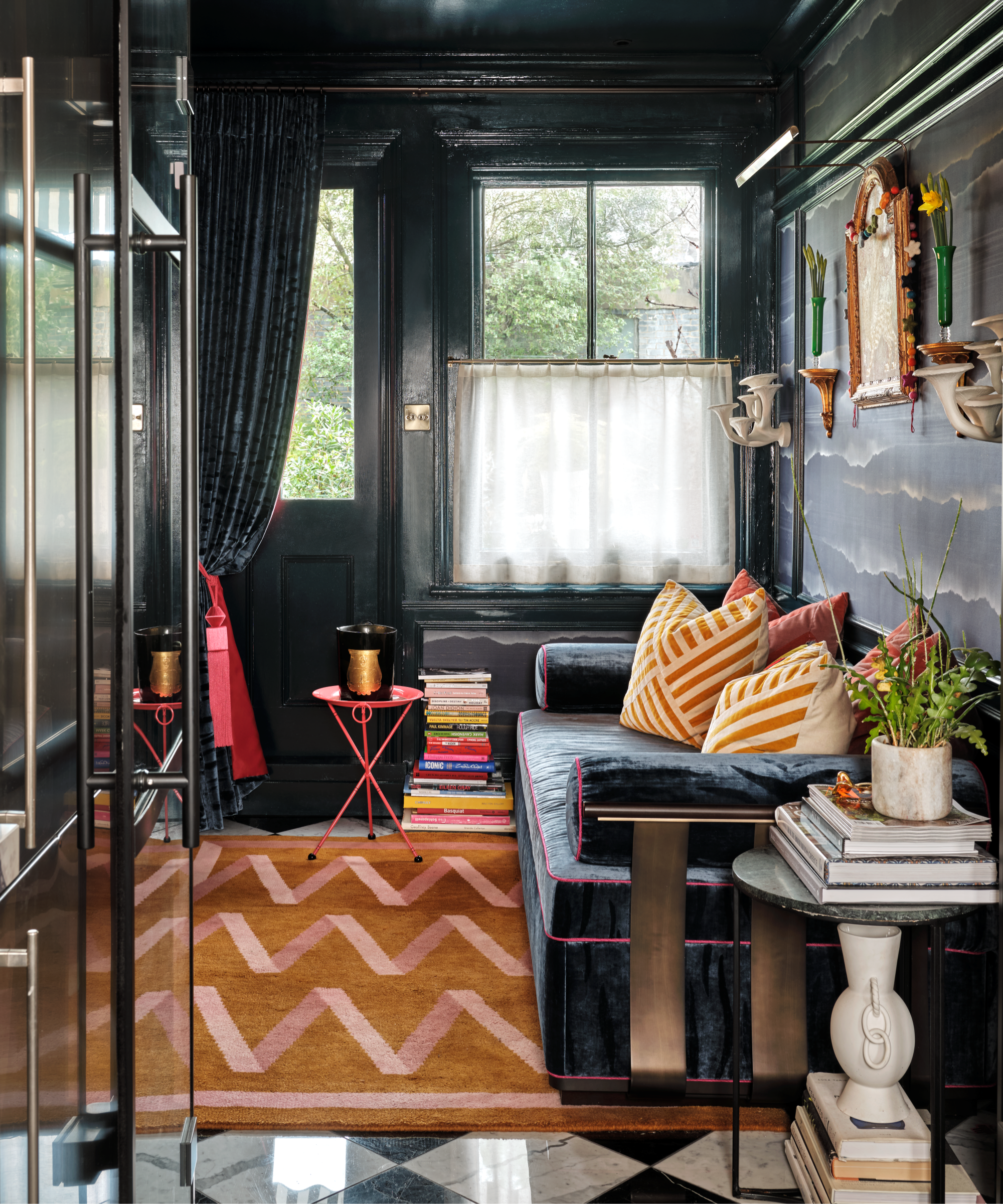 une pièce confortable avec des murs sombres, un canapé sombre et un tapis orange vif avec des lignes roses en zigzag