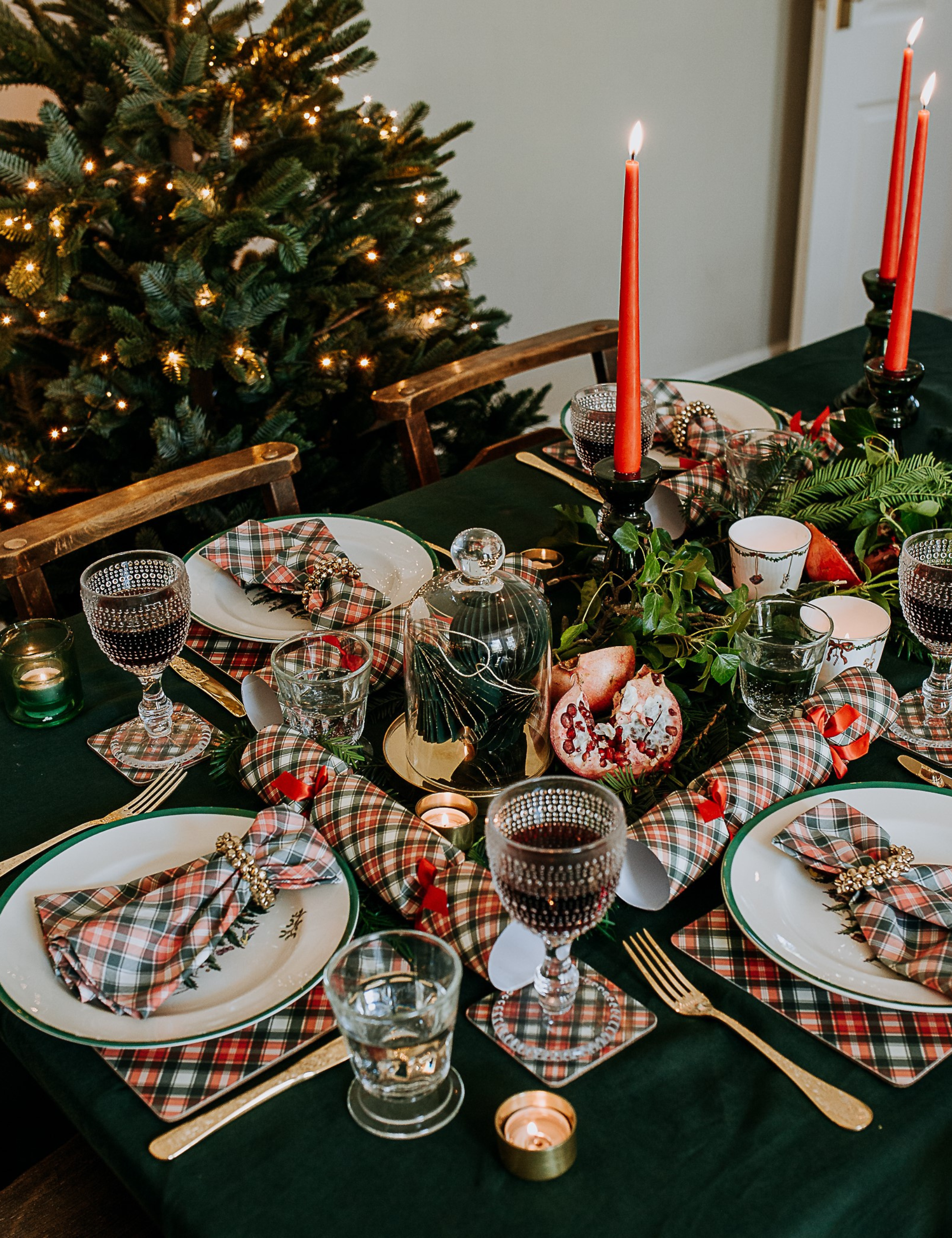 Décoration de table de Noël Ralph Lauren comprenant du linge de table vert chasseur et tartan, des bougies coniques rouges et des couverts en laiton.
