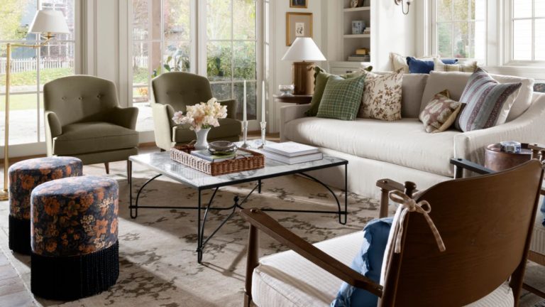 La nouvelle collection de McGee & Co. est un aperçu de toutes les plus grandes tendances printanières à venir en 2026 a living room with a large beige couch with pillows on top, two green accent chairs, a large coffee table with decor on top, and two floral ottomans