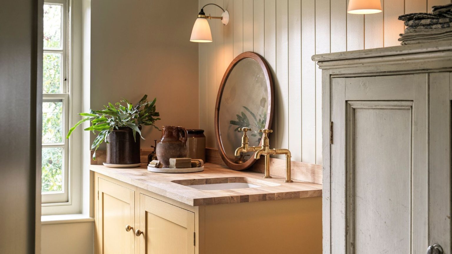 5 choses que les personnes ayant une salle de bain bien rangée ont toujours – Volez vous-même ces victoires organisationnelles chics, utiles et abordables A yellow painted vanity unit with a wooden top. Two brass taps, and an inset sink