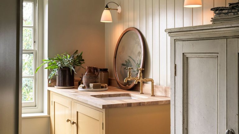 A yellow painted vanity unit with a wooden top. Two brass taps, and an inset sink