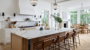 Oubliez tout ce que vous pensez savoir sur les cuisines blanches – Ce remodelage est une leçon pour rendre ce neutre cool confortable et plein de caractère. A neutral kitchen with a wooden island, marble countertops, and a dining space at the far end