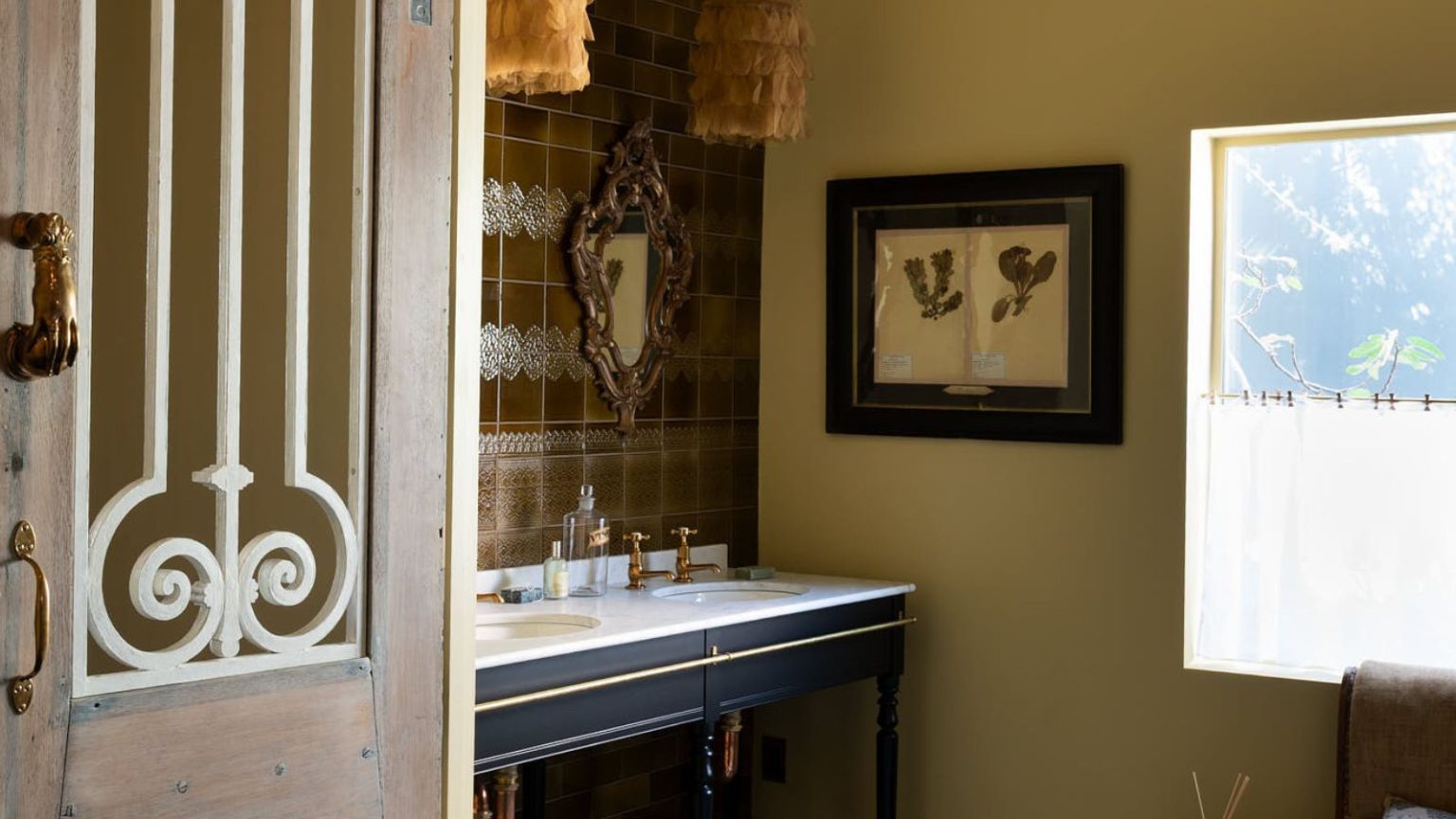 5 caractéristiques de salle de bain traditionnelles qui font leur grand retour – et comment les concepteurs les font fonctionner en 2026 A Traditional bathroom with a double sink washstand, warm neutral walls, and vintage art
