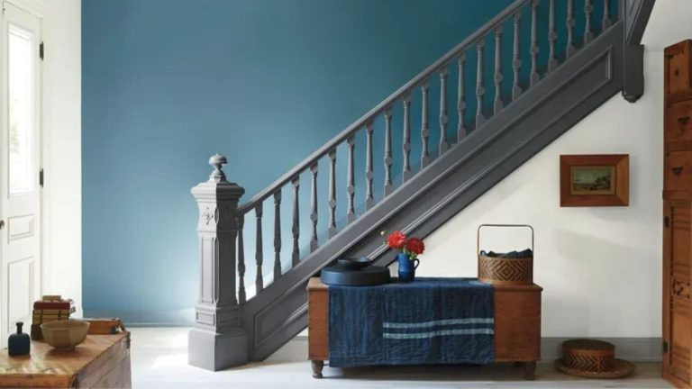 Entryway with blue painted wall, grey painted staircase, wooden console table and vintage decor