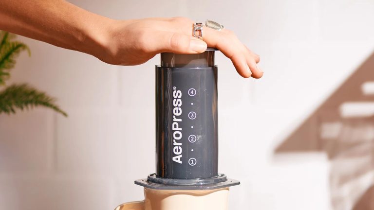L’AeroPress Original à 35 $ est un cadeau pour la Saint-Valentin que les amateurs de café utiliseront réellement : préparez un café riche et onctueux n’importe où AeroPress Original being pressed in front of a wall
