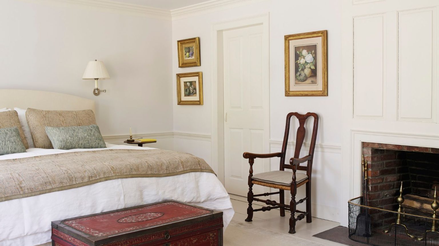 Que dit la couleur de votre chambre sur vous ? Des experts en Feng Shui expliquent la psychologie derrière vos choix Bedroom with white walls, fireplace, bed with beige bedding, vintage red painted trunk and antique art and chair