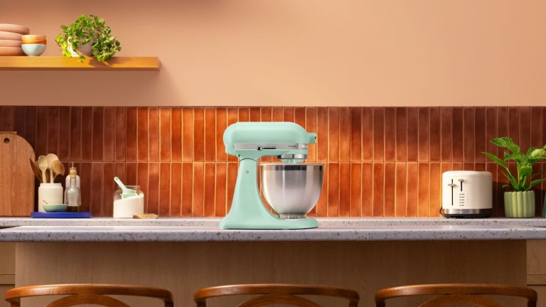La couleur « absolument intemporelle » de l’année 2026 de KitchenAid est arrivée – et elle pourrait être le rafraîchissement chic que votre cuisine attendait A spearmint blue stand mixer on a kitchen island, with terracotta colored tiles in the background.