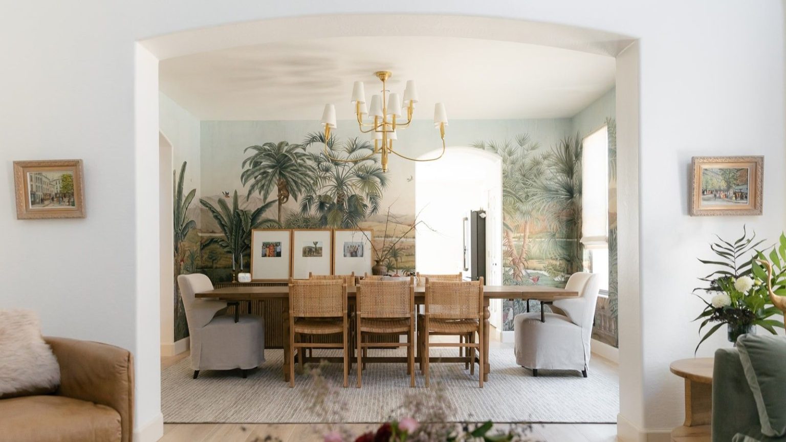 Si votre bac à vide vous fait éternuer, ce requin sans fil à vidage automatique change la donne pour les personnes allergiques – maintenant avec 150 $ de réduction White interior archway revealing dining room with floral scene wallpaper and dining table with rattan chairs on white rug. Pictured in the foreground are an armchair, two framed pictures, and a side table with flowers.