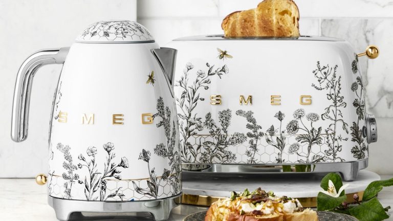 Appareils de décoration en nid d’abeille ? La tendance fantaisiste de la cuisine 2026 que vous n’avez pas vue venir A SMEG kettle and toaster with grey flower and bee motifs on white bases, with stainless steel accents.