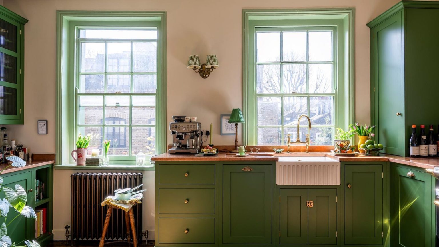 Adieu les éviers de cuisine encombrés – 16 accessoires élégants qui gardent les choses organisées A small kitchen with green cabinets, copper countertops, warm neutral walls, and a fluted sink