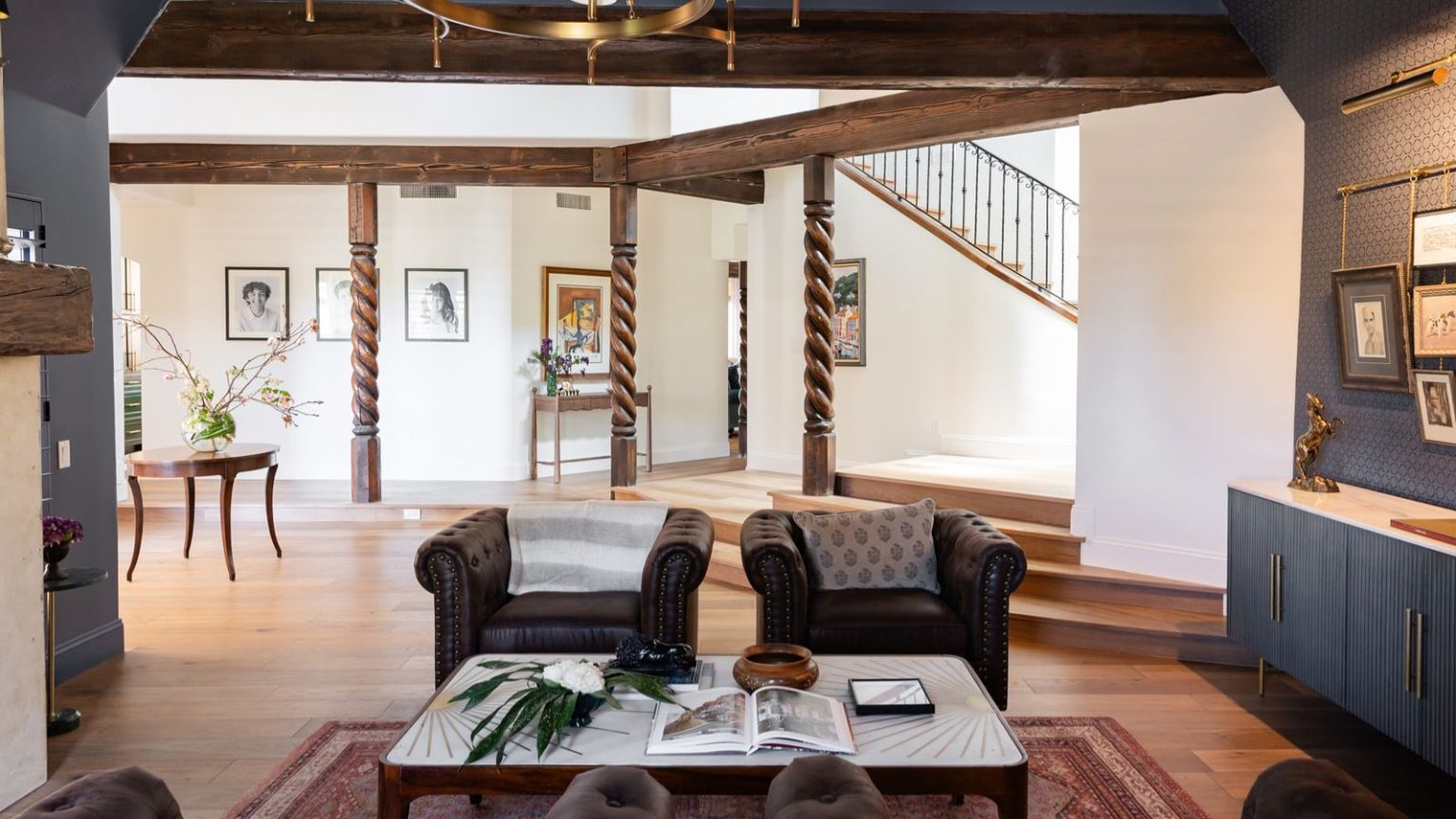 Ne coupez plus jamais les cheveux de votre aspirateur – Ce Dyson met fin aux emmêlements et bénéficie désormais de 200 $ de réduction Living room space with wooden pillars and beams, two leather armchairs, a lined coffee table with an open magazine, blue walls and cabinets. Pictured behind is a large open space with a round side table and framed pictures.