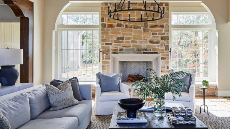 Découvrez comment cette maison de Lake Martin rend le « luxe rustique » réellement adapté aux familles neutral living room with brick fireplace and gray and white sofas and armchairs