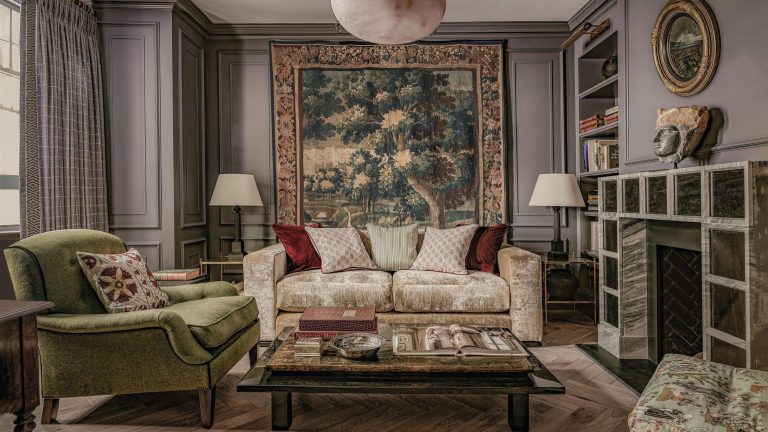 Un designer new-yorkais prouve que Dusty Mauve est le nouveau neutre pour 2026 dans cette maison d’enfance londonienne réinventée a mauve living room with a large vintage tapestry, wall paneling, a unique square fireplace, cream velvet sofa and green armchair