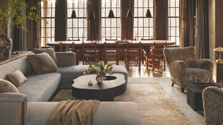 Nous l’appelons : « Moody Farmhouse » est le nouveau style rustique – 18 pièces chics pour une maison plus sombre et axée sur la texture Moody farmhouse living room-dining room combo, featuring neutral, texture-rich furniture, large windowpane panels and a row of rustic pendant lights