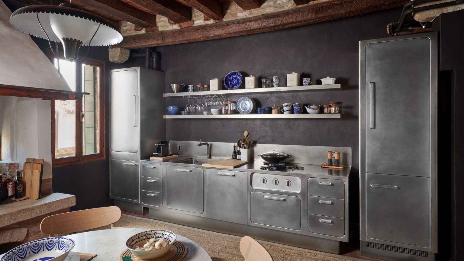 Non, l’acier inoxydable n’est pas réservé aux cuisines minimalistes des années 90 : cette petite cuisine italienne prouve qu’elle peut s’adapter parfaitement au bois et à la pierre. A one-wall stainless steel kitchen with retro-style units and wood accents