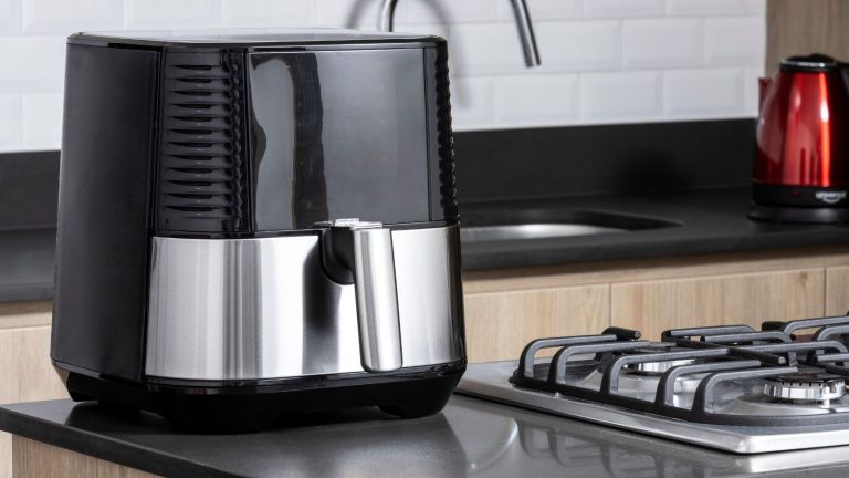J’avais tort : ce revêtement non toxique à 10 $ accélère en fait le nettoyage de la friteuse à air, et je n’en suis pas fou A black and silver air fryer on a kitchen side