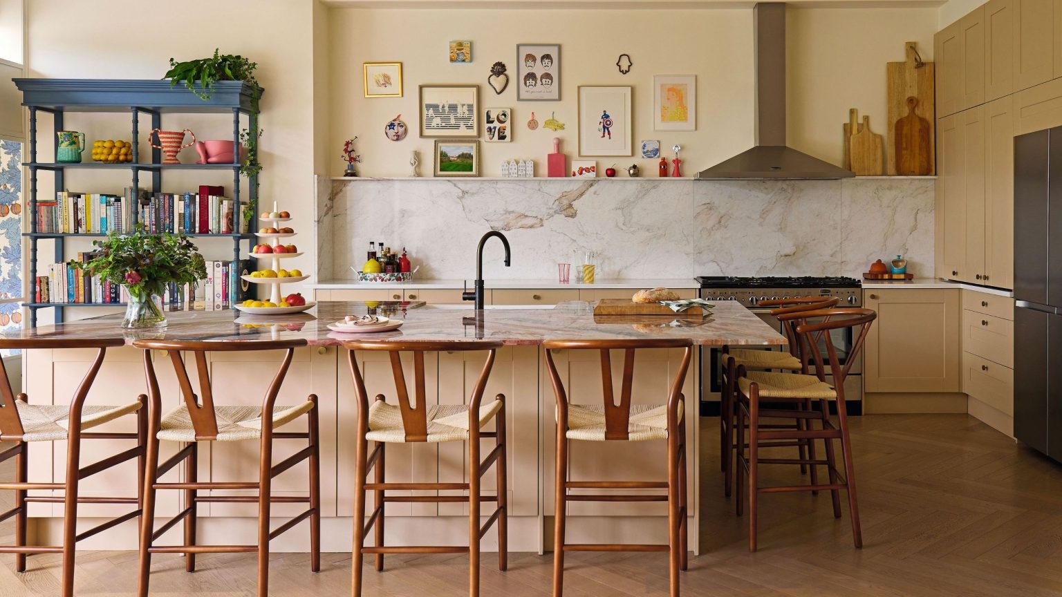 Neutral kitchen featuring veiny cream colored marble and a large island, accented by mid-century bar seats and colorful eclectic accents