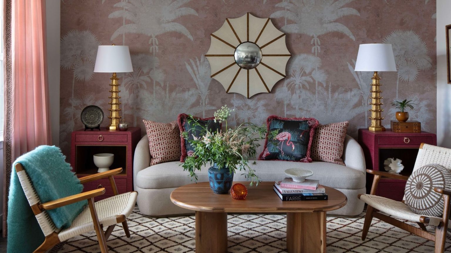 Arrêtez de « ramer » votre aspirateur et de laisser un tiers des poils de votre animal derrière vous – Cette règle de hachures croisées à 90 degrés nettoie chaque fibre de tapis. Vibrant living room with pink-and-white 'tree' wallpaper with a mirror and pink curtains. In the room, a sofa, two armchairs, a wooden coffee table, two side tables with lamps, and a patterned rug are pictured.