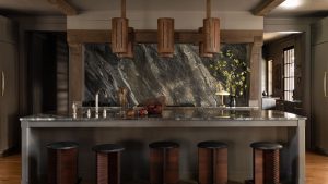 Les cuisines de ferme n’ont pas besoin d’être claires et aérées – ce projet Moody Alabama prouve que le marbre foncé peut être tout aussi invitant Open-plan farmhouse kitchen with a large marble island, dark marble backsplash, reclaimed wood beams, and vintage wooden stools.