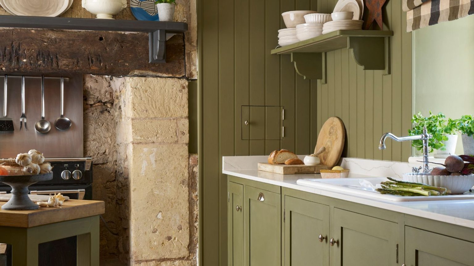 J’ai failli provoquer un incendie dans ma cuisine avec l’emplacement de ma friteuse à air – Voici la leçon clé à tirer de mon erreur A green painted kitchen, with a traditional brick fireplace surrounding a stove. White worktops.