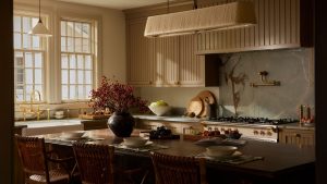 Les cuisines neutres ne doivent pas nécessairement être ennuyeuses : cette conception prouve qu’une forte matérialité et des textures réfléchies sont les principes fondamentaux d’un projet invitant. A warm neutral kitchen with slatted cabinets, a table-style island, and blue stone countertops and backsplash