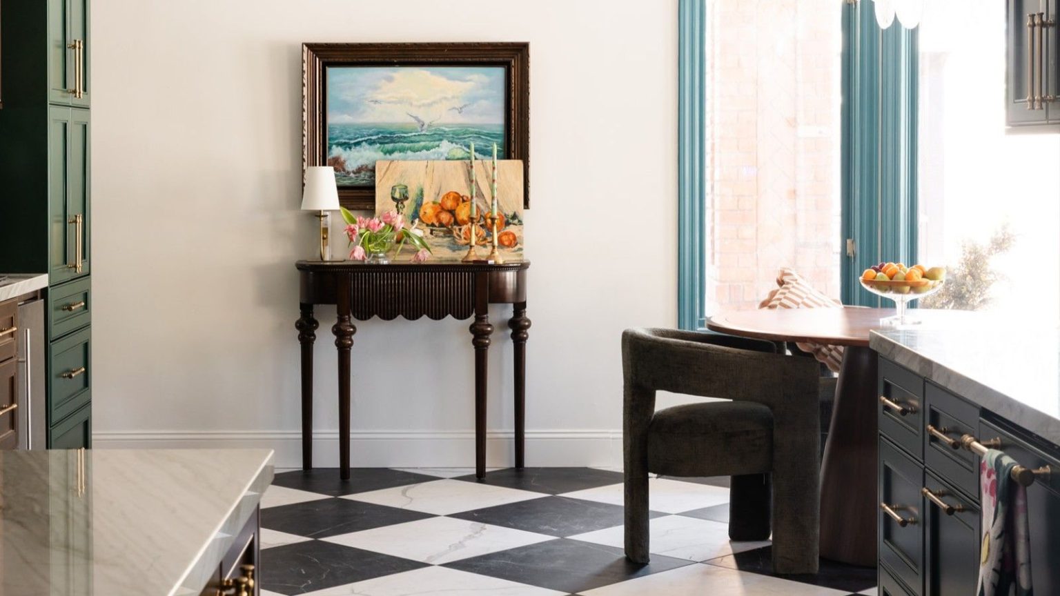 Arrêtez de frotter vos sols tous les soirs – Cet aspirateur robot Dreame met fin à la « boucle infinie » de la boue et du désordre printaniers Kitchen/dining space with black-and-white tile floor. A side table is against the wall in the background with a lamp, flowers and candles, below a framed painting. Corners of shiny countertops are pictured in the foreground.