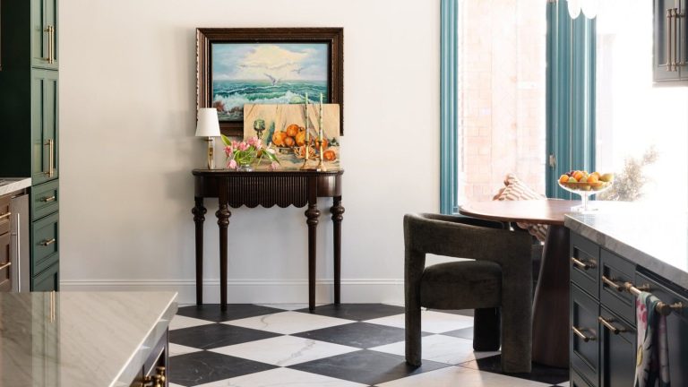 Arrêtez de frotter vos sols tous les soirs – Cet aspirateur robot Dreame met fin à la « boucle infinie » de la boue et du désordre printaniers Kitchen/dining space with black-and-white tile floor. A side table is against the wall in the background with a lamp, flowers and candles, below a framed painting. Corners of shiny countertops are pictured in the foreground.
