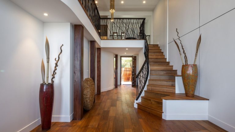 Évitez le Dyson : cet aspirateur à 147 $ vous montre la poussière dont vous ignoriez l’existence, puis l’aspire rapidement Large, modern entryway with wooden staircase and wooden floors, and large ornate vases. Second floor is partially pictured behind black banister.