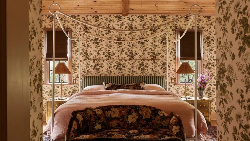 Pattern-drenched floral bedroom featuring a whimsical iron four poster bed, accented by woven table lamps and a striped headboard