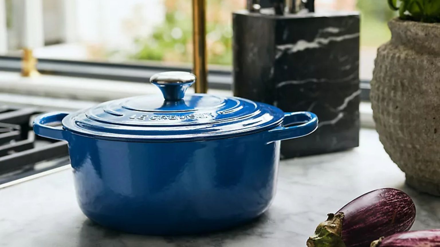 Je ne m’attendais pas à aimer ces protecteurs de batterie de cuisine Le Creuset – ils font une telle différence dans mon petit rangement de cuisine, maintenant je ne vivrai plus sans eux A dark blue Le Creuset Dutch oven on a marble kitchen counter