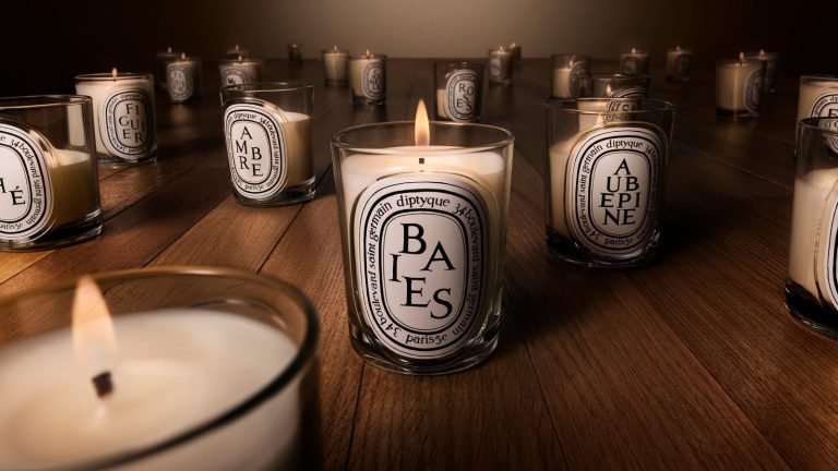 Diptyque relance ses bougies de luxe avec une grande mise à niveau en matière de durabilité et cinq nouveaux parfums – parfaites pour offrir en cadeau pour la fête des mères Diptyque relaunch candles in glass vessels with white labels and black text, pictured on a wooden surface