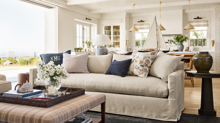 Shea McGee vient de sortir sa collection d’été – et ces 3 tendances marquantes sont des classiques instantanés a coastal-inspired living room with a large beige couch, several throw pillows, a plaid coffee table, decor on top, and a side table with a vase on top