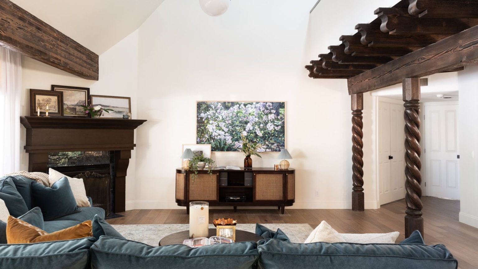 La seule partie de votre aspirateur sans fil que vous oubliez de nettoyer (et cela tue votre aspiration) Large living room space with blue sofa, wooden beams, a retro media unit, a piano, and framed artwork on white walls.