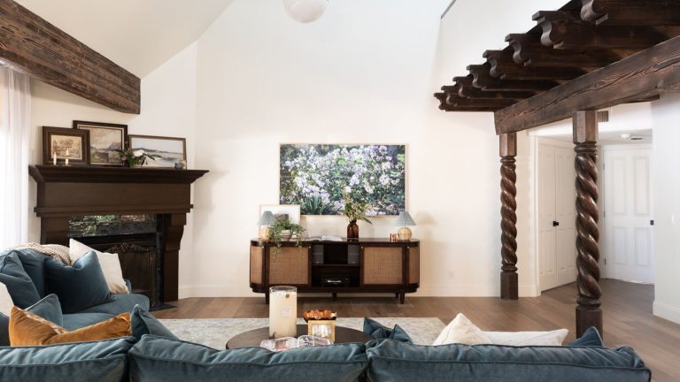 La seule partie de votre aspirateur sans fil que vous oubliez de nettoyer (et cela tue votre aspiration) Large living room space with blue sofa, wooden beams, a retro media unit, a piano, and framed artwork on white walls.