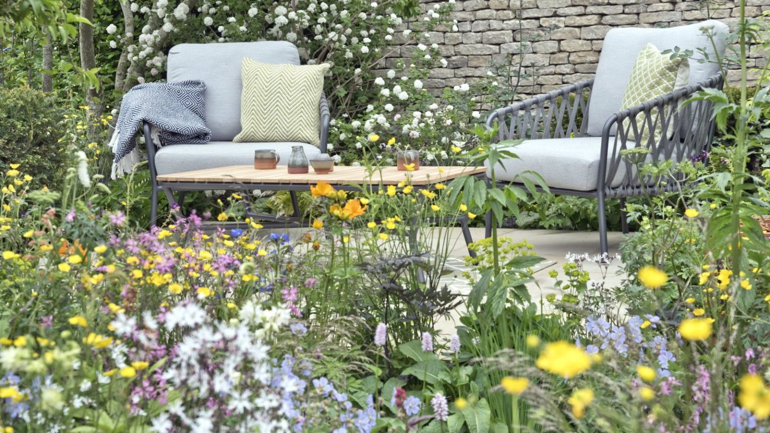 La nouvelle chaise à bascule de jardin « pliable » d’ALDI transformera votre jardin en une évasion privée pour moins de 50 $ A colourful flower bed in front of a paved seating area in a garden