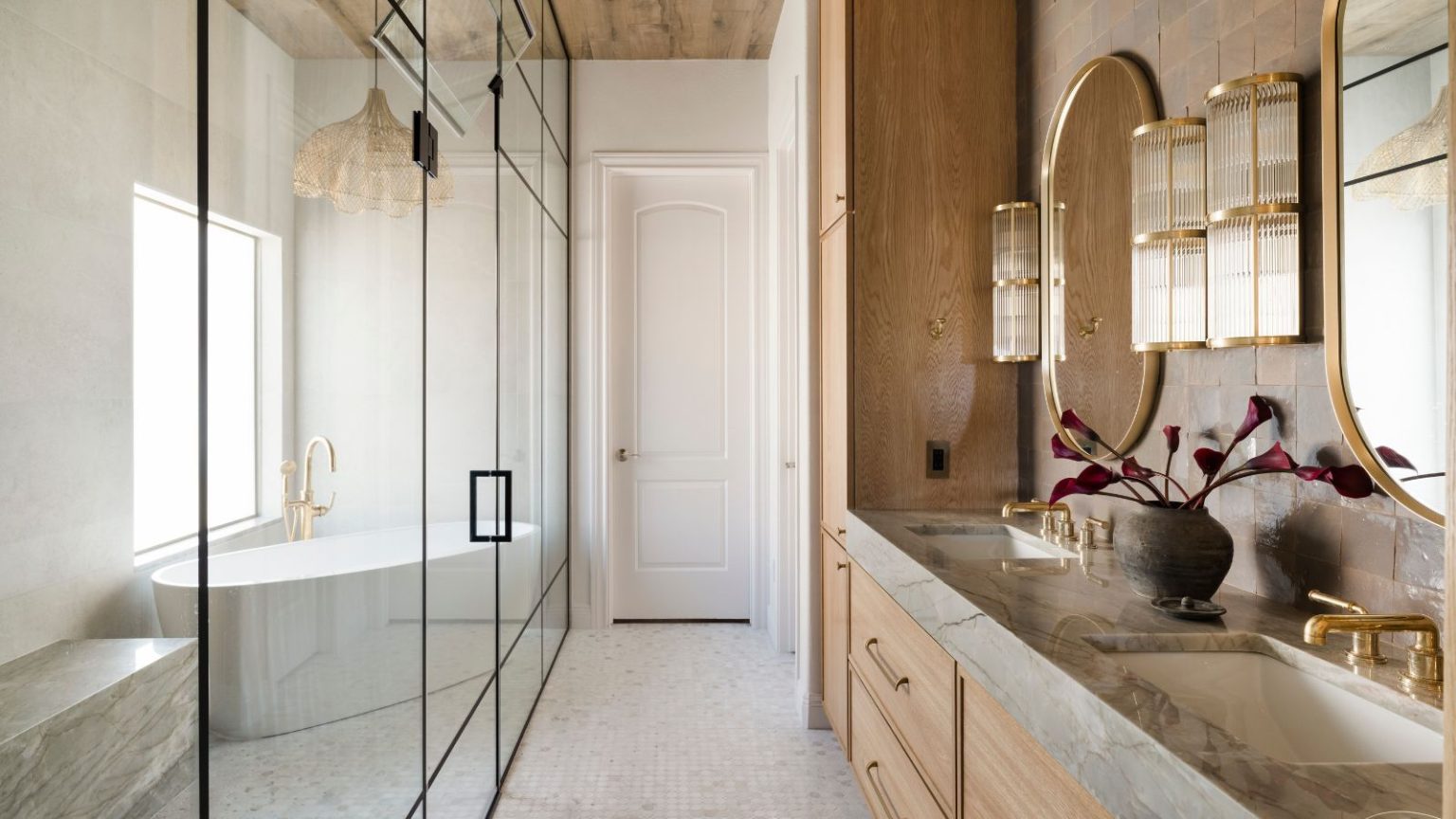 A broken plan bathroom with a glass screen separating the wooden vanity from the wet room