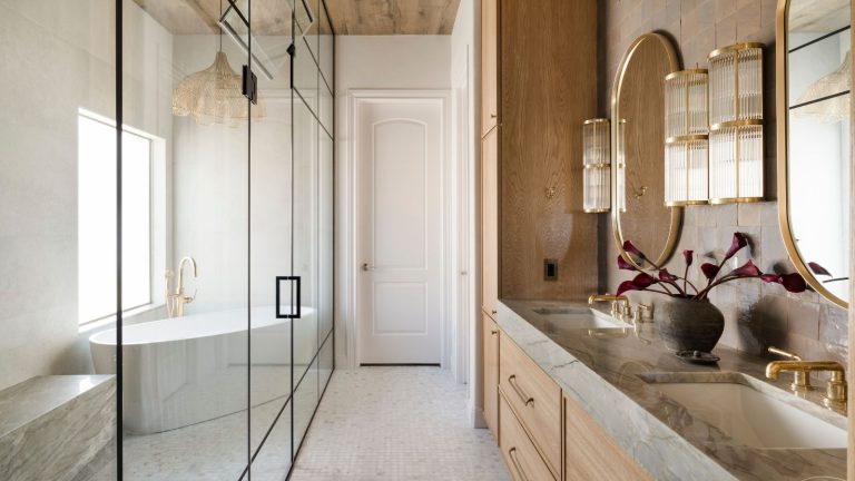 A broken plan bathroom with a glass screen separating the wooden vanity from the wet room