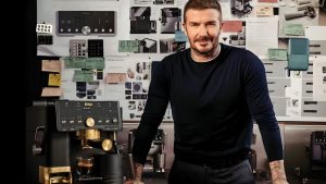 David Beckham vient de concevoir une élégante cafetière en édition limitée avec Ninja – c’est une mise à niveau chic cinq étoiles pour votre comptoir David Beckham stands in front of a large vision board, beside a black and gold coffee maker.