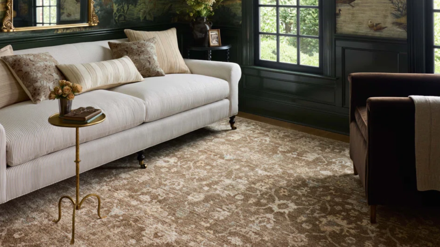 La marque que les designers d’intérieur achètent toujours chez Wayfair organise une vente massive a cozy living room with a large area rug, a cream couch, a small drink table, and dark blue painted walls