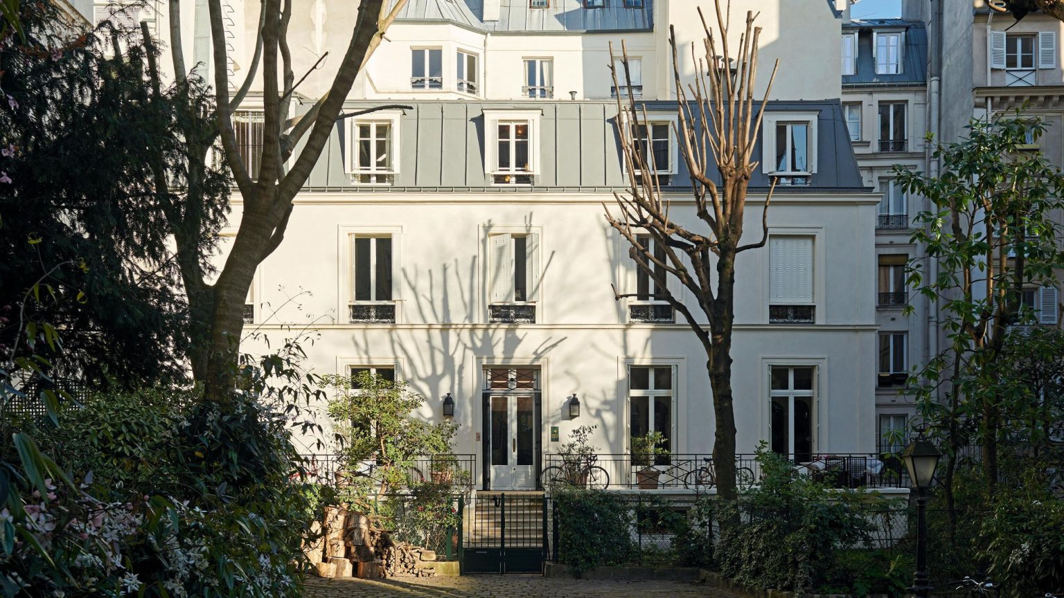 Entrez dans une maison parisienne conçue comme une série de mondes oniriques, où chaque pièce révèle un moment inattendu the exterior of a large Parisian apartment with a garden full of trees